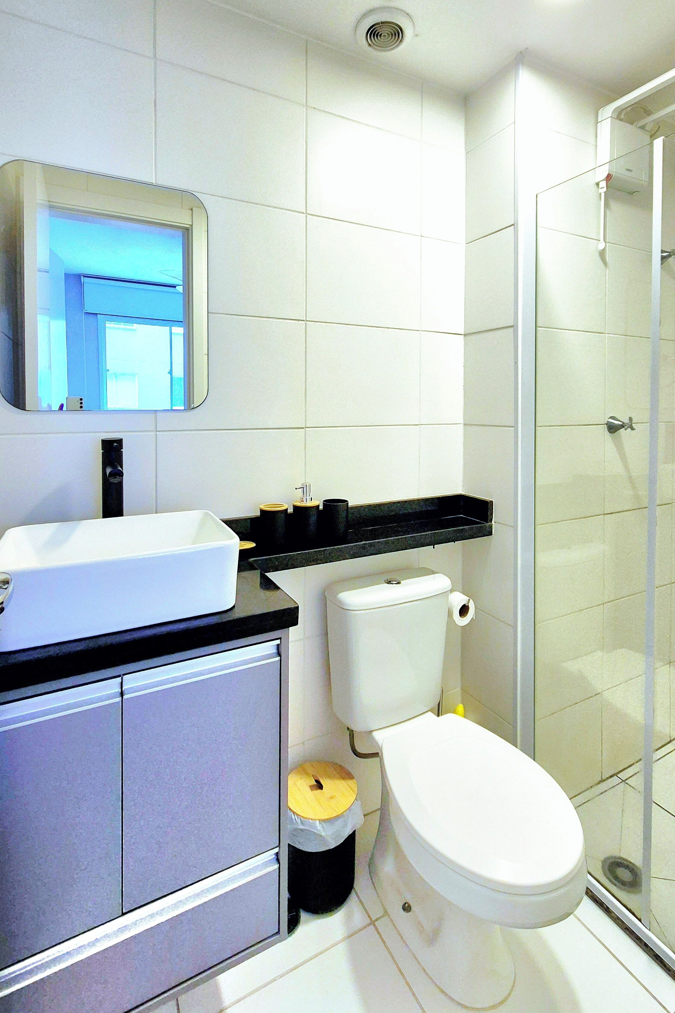 Un baño moderno con lavamanos, inodoro y ducha blancos.