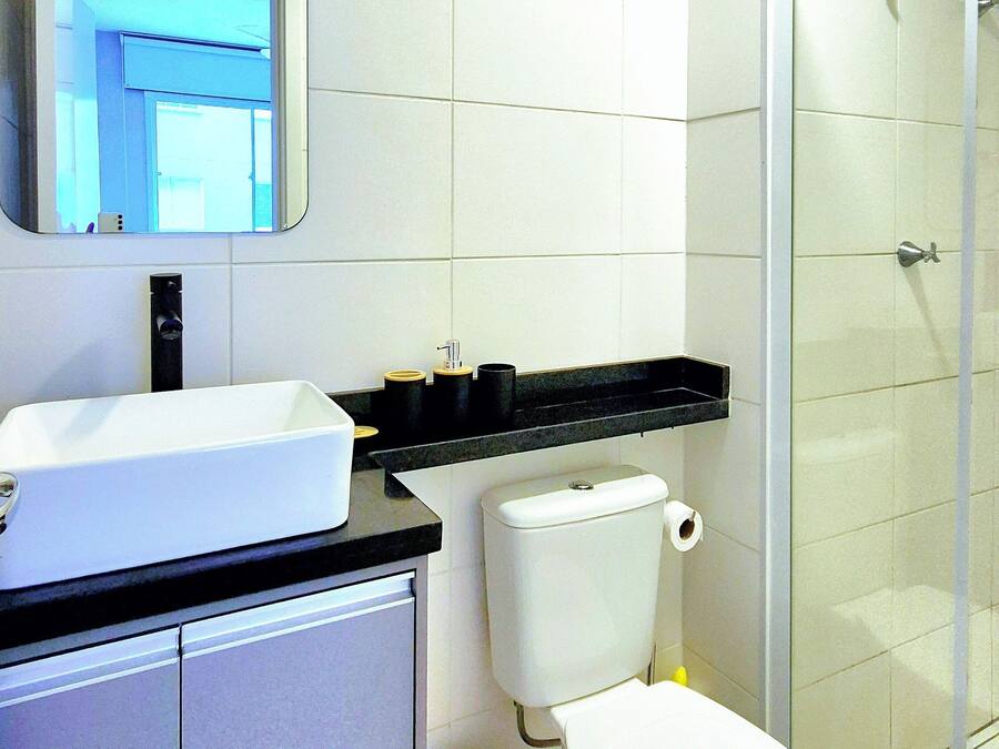 Un baño moderno con lavamanos, inodoro y ducha blancos.