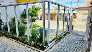 Una entrada con paredes de vidrio y un camino pavimentado que lleva a un edificio.