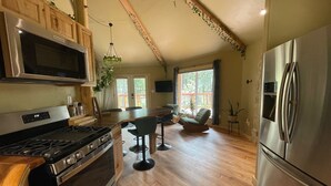 A spacious kitchen with wooden cabinets, a stainless steel stove, a refrigerator, and a dining area with a wooden table and chairs.