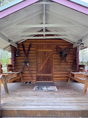 Un chalet rustique avec une porte en bois, un banc et un paillasson.