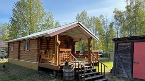 Eine Blockhütte mit Veranda, Holzstufen und einem kleinen Schuppen.