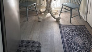 Eine Küche mit einem modernen Kühlschrank, einem Esstisch mit zwei Stühlen und einem gemusterten Teppich.
