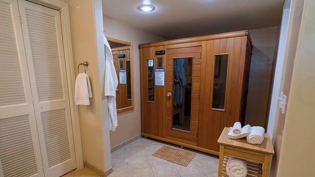 Un sauna avec des portes en bois, un porte-serviettes et une petite table sur laquelle sont posées des serviettes.