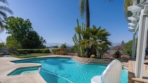 Une piscine à l’eau d’un bleu cristallin, entourée de palmiers et offrant une vue sur les montagnes.