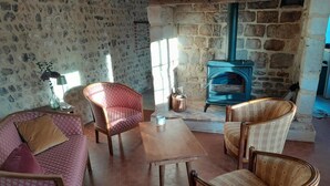 A cozy living room with a stone fireplace, patterned furniture, and a tiled floor.