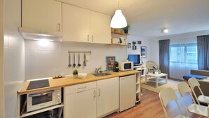 Una cocina compacta equipada con microondas, horno y lavabo. Hay una zona de comedor con mesa y sillas.