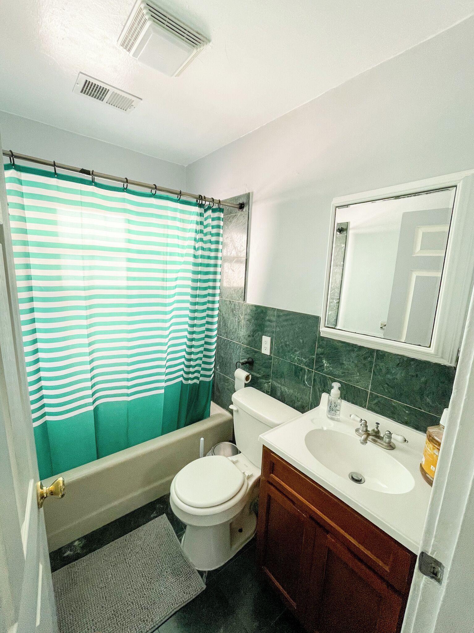 A bathroom with a toilet, sink, and shower curtain.