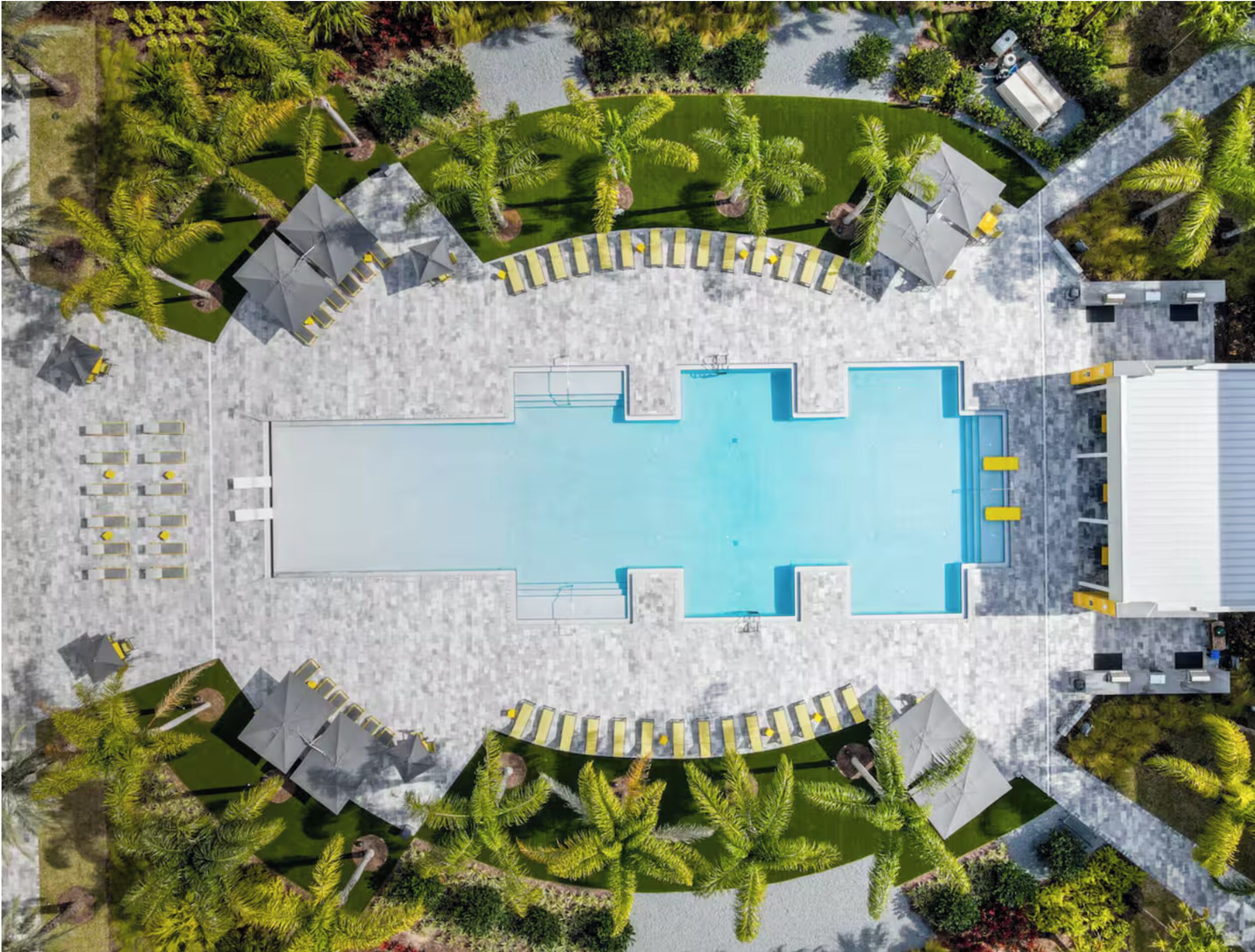 Luchtbeeld van een hotel met een centraal gelegen zwembad, omringd door palmbomen en een overdekt zitgedeelte.
