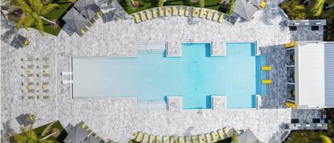 Luchtbeeld van een hotel met een centraal gelegen zwembad, omringd door palmbomen en een overdekt zitgedeelte.
