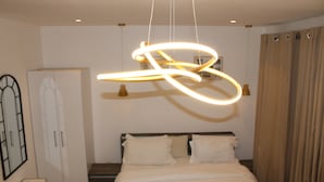Una camera da letto con un letto, un armadio, una lampada a sospensione e una tenda.