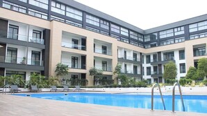 Un hotel moderno con piscina, numerosi balconi e aree salotto all'aperto.