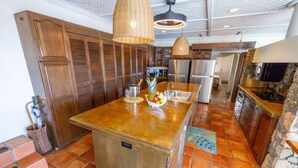 A kitchen with a central island, wooden cabinets, a stone wall, and a hanging light fixture.
