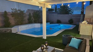 A backyard with a swimming pool, a patio area with seating, and a pergola with string lights. - The Vegas Villa, Entire Home in Las Vegas, Nevada (Las Vegas)