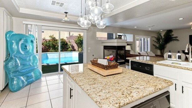 A modern kitchen with granite countertops, a built-in dishwasher, and a large window overlooking a pool. - The Vegas Villa, Entire Home in Las Vegas, Nevada (Las Vegas)