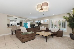 A spacious living room with a sectional sofa, a coffee table, and a large potted plant.