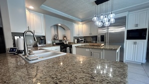 A modern kitchen with granite countertops, stainless steel appliances, and white cabinetry. - The Vegas Villa, Entire Home in Las Vegas, Nevada (Las Vegas)
