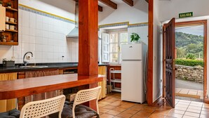 Een keuken met een houten tafel, stoelen, een koelkast en uitzicht op de omgeving.