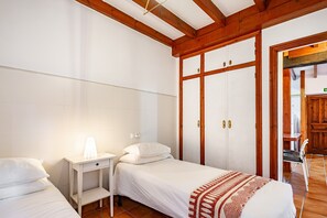 A bedroom with two single beds, a bedside table with a lamp, a wardrobe, and a chair.
