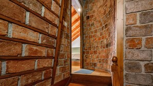 A staircase with wooden steps leading to a room with brick walls and a wooden ceiling.