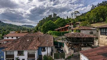 Un pueblo tradicional con edificios de tejados de terracota, un puente de piedra y abundante vegetación.