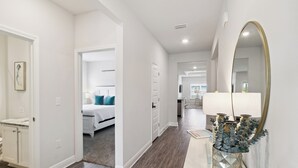 A hallway with a bed, a mirror, and a decorative vase. - Falling Star Retreat is a 4BA/2BA coastal home, just 900 feet to the beach, pet friendly! (Port St. Joe)