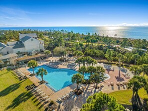 Ein Resort mit großem Pool, Liegebereichen und Meerblick.