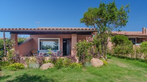 Una casa con techo de tejas, una puerta y una ventana. Hay una silla y una mesa afuera.