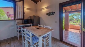 Un comedor con una mesa de madera, sillas blancas, un tazón negro y un televisor.