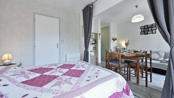 Un dormitorio con cama, escritorio, silla, mesa de comedor y sofá.