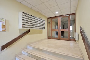 A staircase leading to a door with a glass panel, a wall-mounted filing cabinet, and a bulletin board.