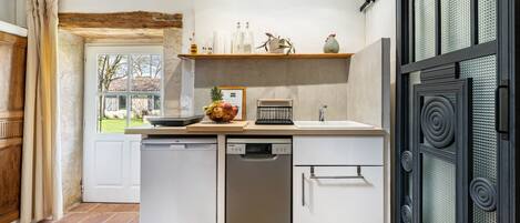 A compact kitchen with white cabinetry, a dishwasher, a sink, and a decorative shelf with kitchen items.