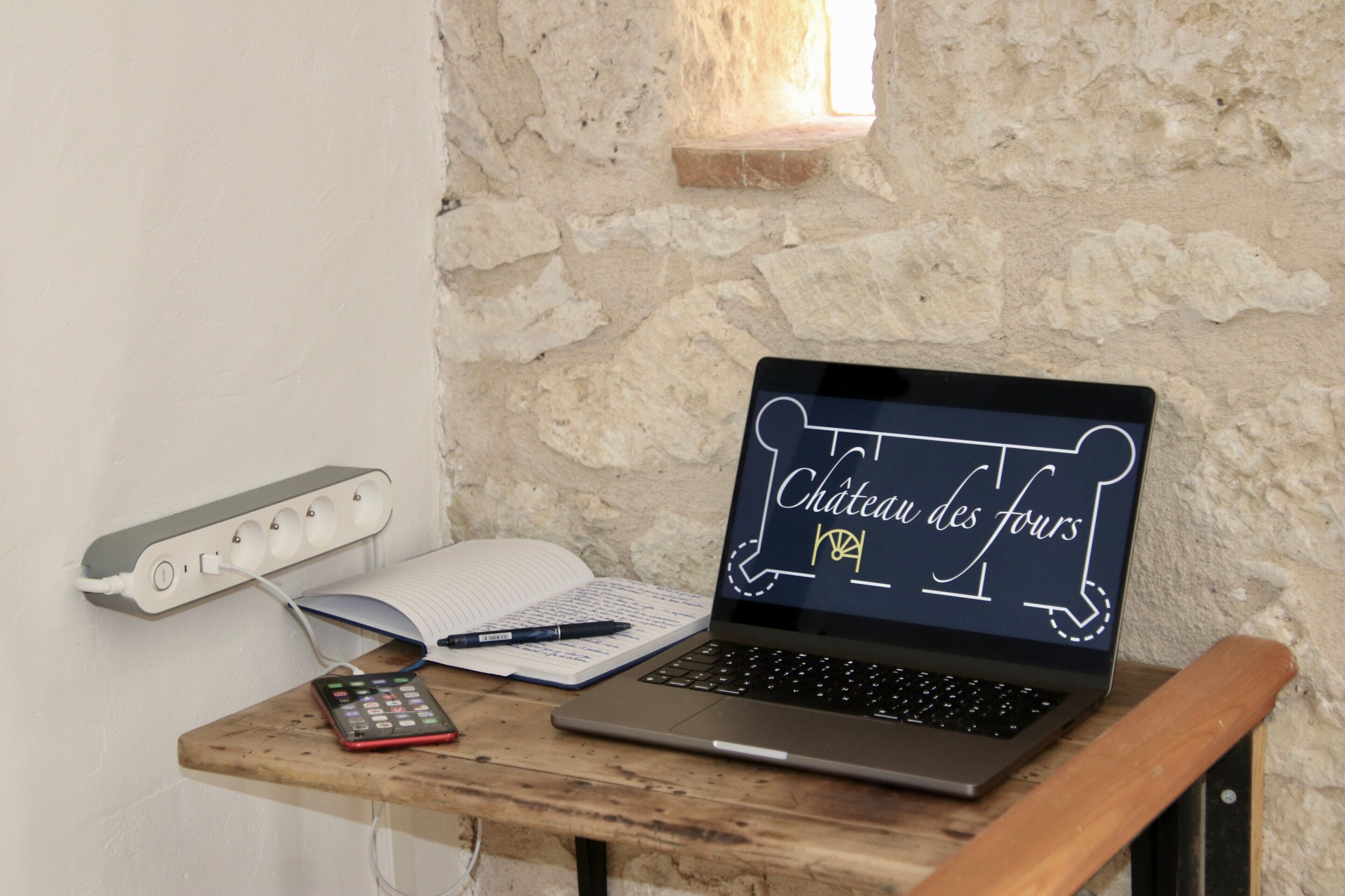 Una computadora portátil sobre una mesa de madera, con un cuaderno, un bolígrafo y una calculadora.