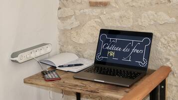 A laptop on a wooden table with a notebook, pen, and a calculator.
