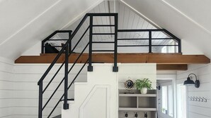 Ett rum i loftstil med en trätrappa, inbyggd förvaring och en bänk.