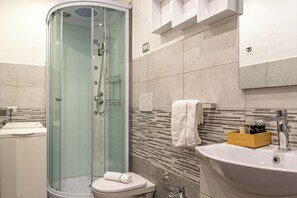 A modern bathroom with a glass-enclosed shower, a sink with a wooden soap dish, and a towel rack.