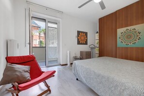 A bedroom with a bed, a red chair, a wooden wardrobe, and a view through a sliding door.