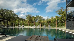A swimming pool with lounge chairs and a wooden table, surrounded by trees and a building. - Verona Hotel (Sile)