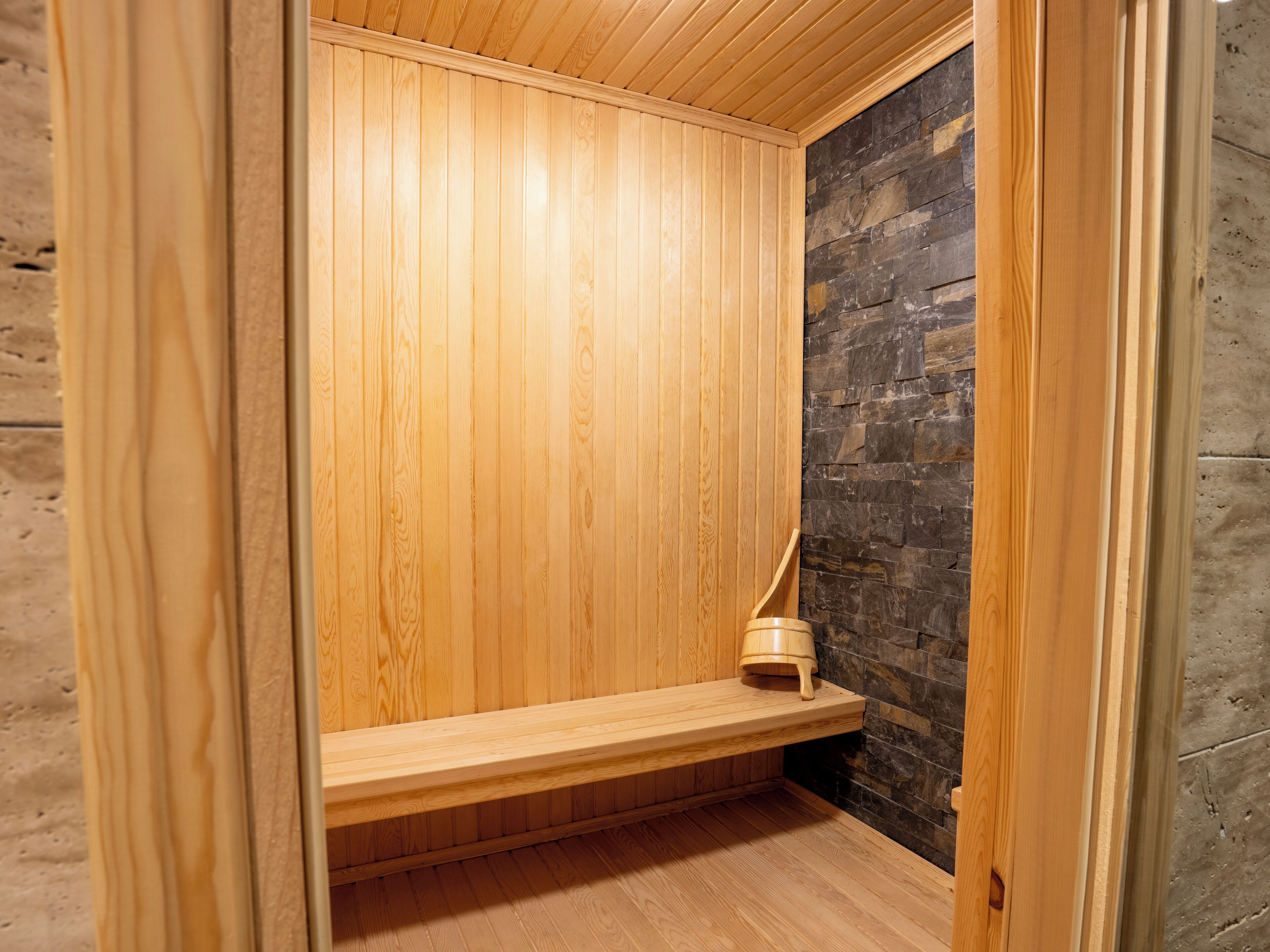 Una sauna de madera con un banco y una pared de piedra.