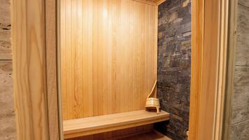 Una sauna de madera con un banco y una pared de piedra.