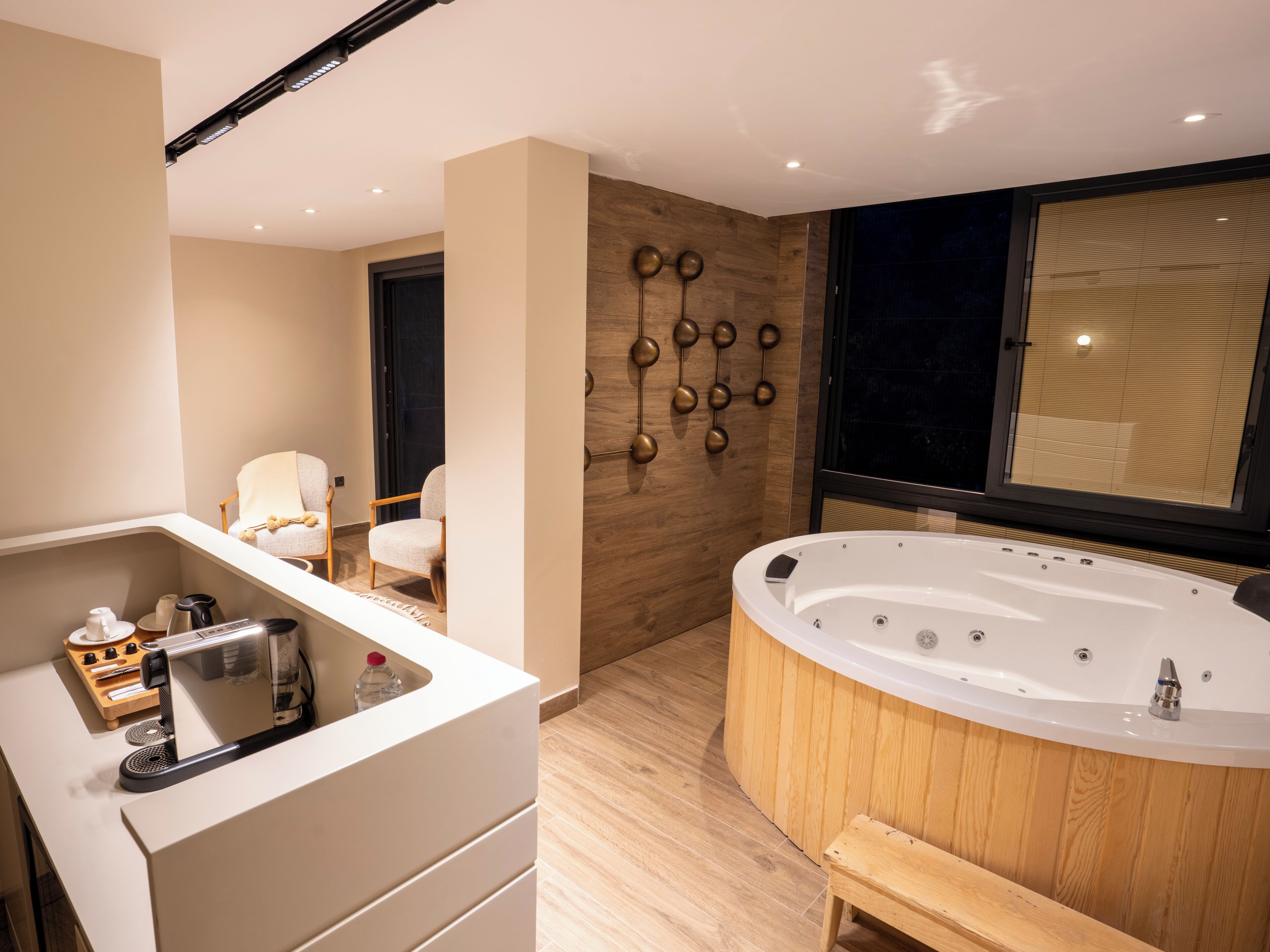 Un baño moderno con tocador de madera, una bañera grande y una zona de estar con sillas.