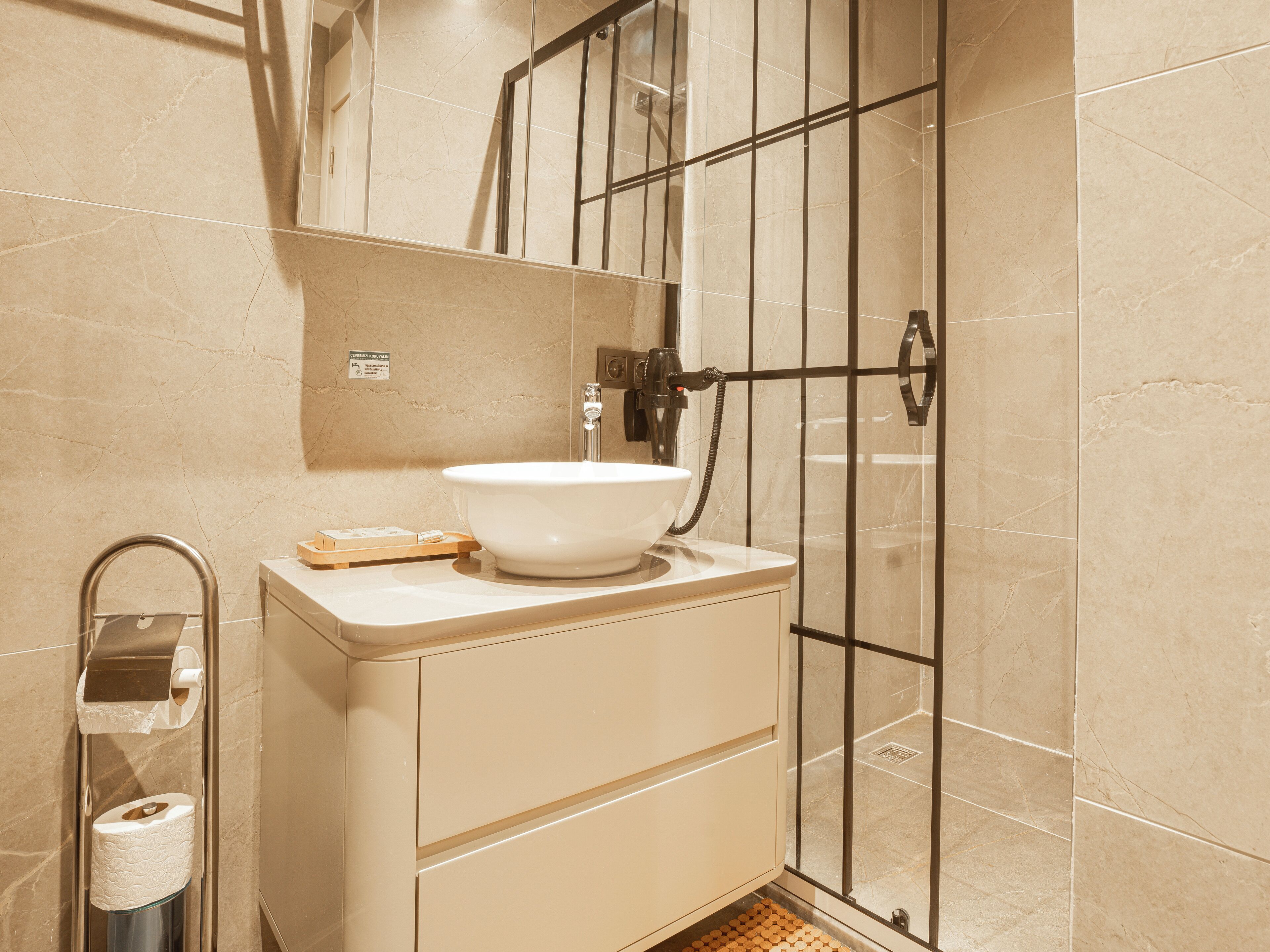 A bathroom with a white sink, a towel dispenser, and a toilet paper holder.