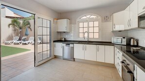 A modern kitchen with white cabinets, a dishwasher, a microwave, and a large window.