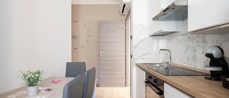 Cocina compacta con encimera de madera, horno integrado y grifo moderno.