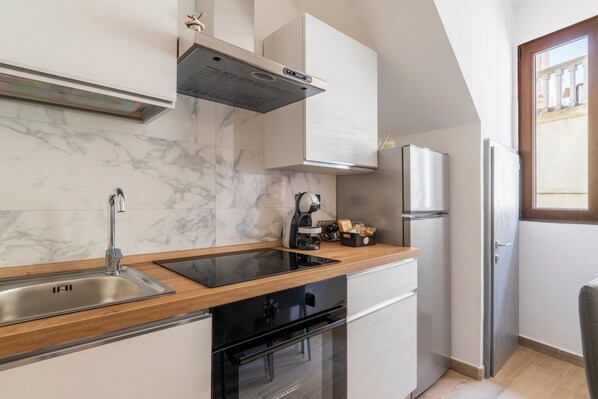 A modern kitchen with a marble backsplash, stainless steel appliances, and a wooden countertop. - Apartment 'Filo Azzurro 1' with Wi-Fi and Air Conditioning (Ulassai)