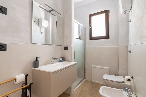Une salle de bain moderne équipée d’un lavabo, d’un miroir, de toilettes et d’une douche.
