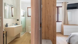 Un dormitorio moderno con un armario de madera, una mesita de noche y un ventanal grande.
