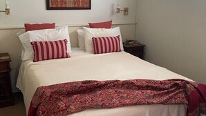 A neatly made bed with a patterned blanket, a wall-mounted clock, and a window with a view of greenery. - Tropical views from spacious, comfortable, well appointed apartment (Palm Cove)