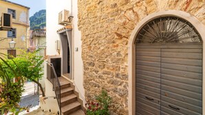 Un bâtiment en pierre avec une porte en métal, un escalier et un petit balcon.
