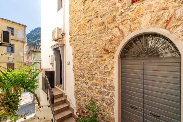 A stone building with a metal door, a staircase, and a small balcony.